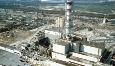 Industrial ruin: shattered buildings and scattered debris around a damaged power plant site with a tall striped lattice tower in the foreground.