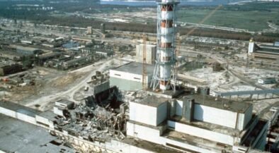 Industrial ruin: shattered buildings and scattered debris around a damaged power plant site with a tall striped lattice tower in the foreground.