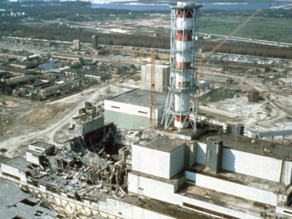 Industrial ruin: shattered buildings and scattered debris around a damaged power plant site with a tall striped lattice tower in the foreground.