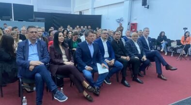 Group of professionally dressed people seated in rows at an indoor conference or seminar hall.