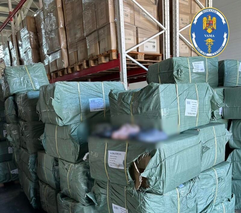 Stacks of green-wrapped bundles on wooden pallets in a warehouse, with a Romanian customs logo visible in the top right corner and labels on the bundles.
