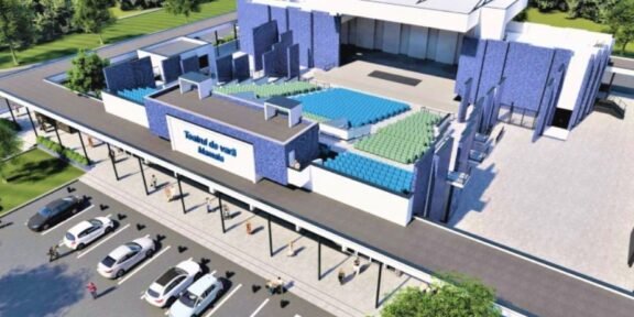 A rendered aerial view of a modern sports arena with blue and green seating, a large entrance, and a parking lot nearby.