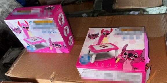 Two pink children's toy sets in colorful cartoon packaging resting on brown cardboard boxes in what looks like a storage area.