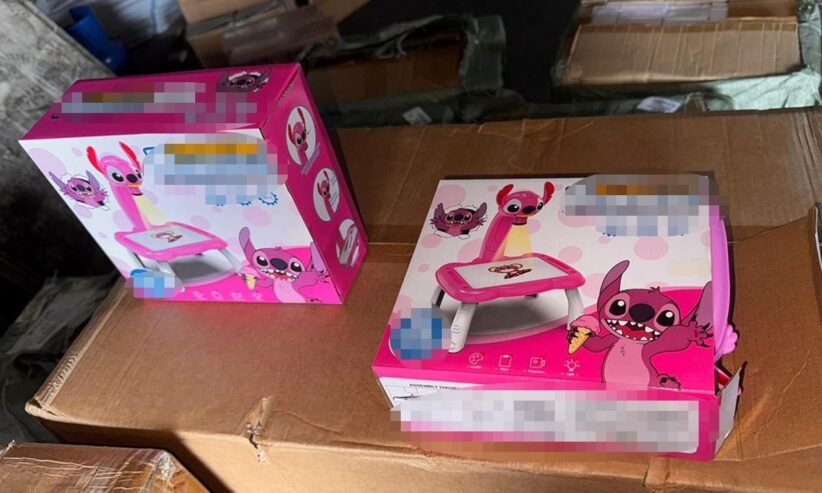 Two pink children's toy sets in colorful cartoon packaging resting on brown cardboard boxes in what looks like a storage area.