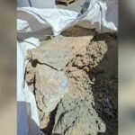 Rubble and loose soil spilling from a white construction bag at a construction site, with jagged rocks and brown dirt visible