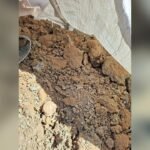 Loose brown soil and small rocks on a construction site, with a black boot partly visible nearby.