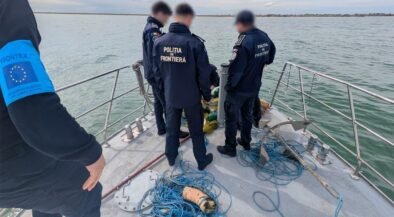 Border police officers on a boat by the water, examining nets and blue ropes on deck.