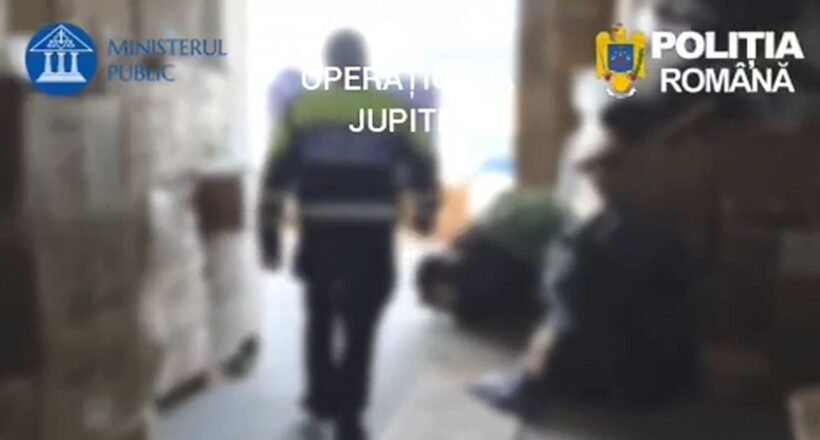 Blurred hallway scene with a uniformed officer walking away; Romanian police logos (Ministerul Public, Poliția Română) are visible in the frame, suggesting a police operation.