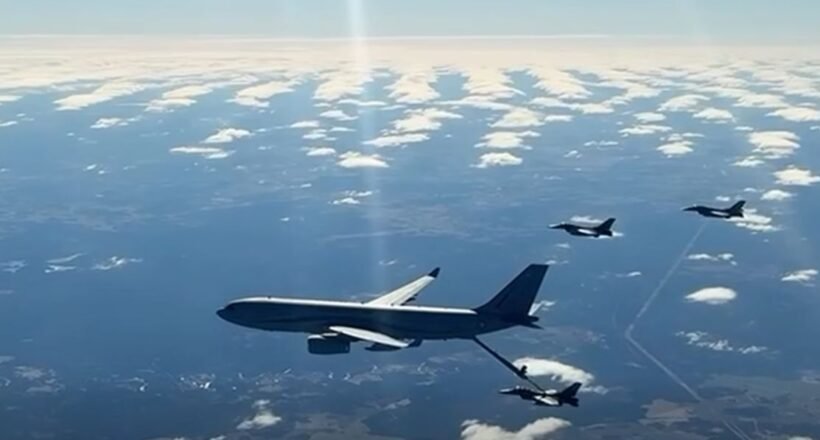 Large military tanker aircraft refuels a fighter jet in mid-air, with other jets nearby over a partly cloudy sky.