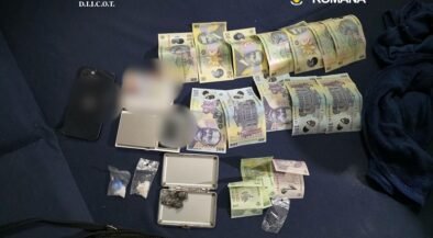 Bundles of money, small bags, and a scale displayed on a dark mat, with DIICOT and Romanian police logos visible