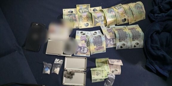 Bundles of money, small bags, and a scale displayed on a dark mat, with DIICOT and Romanian police logos visible