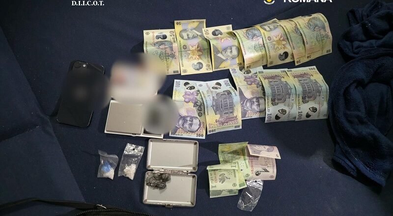Bundles of money, small bags, and a scale displayed on a dark mat, with DIICOT and Romanian police logos visible