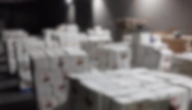 Blurred warehouse scene with stacked white boxes; DIICOT and Poliția Română logos appear in the top corners.