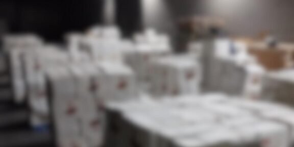 Blurred warehouse scene with stacked white boxes; DIICOT and Poliția Română logos appear in the top corners.