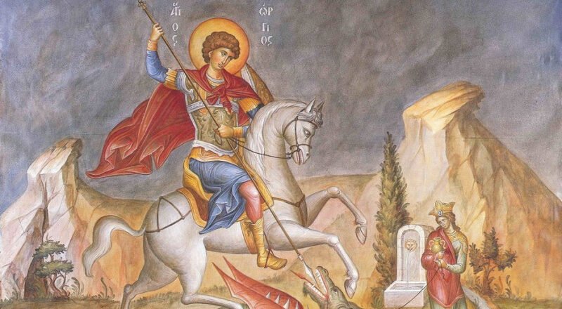 Saint George on a white horse slays a dragon with a spear, red cape billowing, set in a rocky landscape.