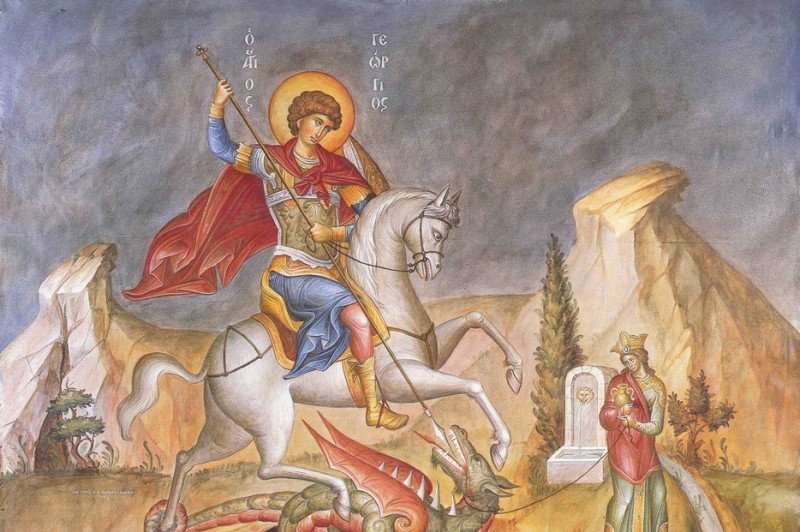 Saint George on a white horse slays a dragon with a spear, red cape billowing, set in a rocky landscape.