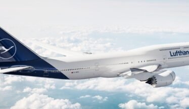 Lufthansa airliner flying above clouds, white fuselage with blue tail and Lufthansa logo