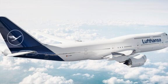 Lufthansa airliner flying above clouds, white fuselage with blue tail and Lufthansa logo