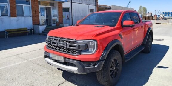 Red Ford Ranger pickup parked in front of a Romanian border police station (Politia de Frontiera) in a paved lot.