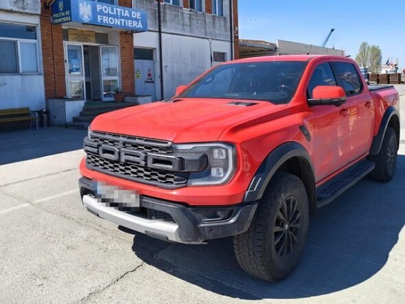 Red Ford Ranger pickup parked in front of a Romanian border police station (Politia de Frontiera) in a paved lot.