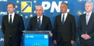Four men in dark suits stand at a blue podium with a microphone, during a PNL press conference with EU-starry backdrop and logos behind them.