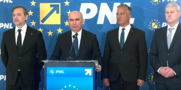 Four men in dark suits stand at a blue podium with a microphone, during a PNL press conference with EU-starry backdrop and logos behind them.