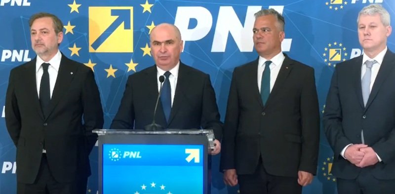 Four men in dark suits stand at a blue podium with a microphone, during a PNL press conference with EU-starry backdrop and logos behind them.