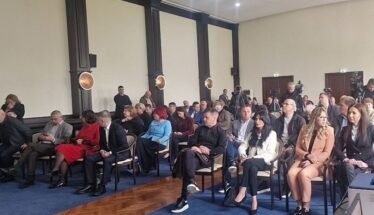 Audience seated in rows in a formal conference room during a presentation/meeting session.