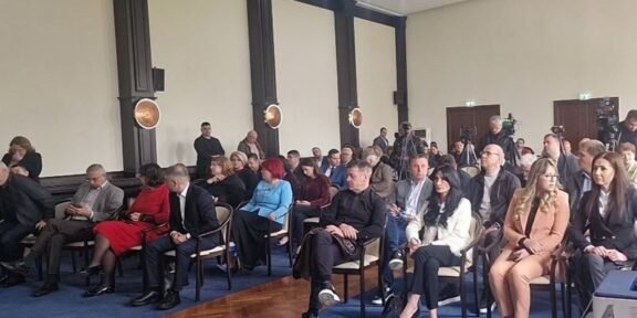 Audience seated in rows in a formal conference room during a presentation/meeting session.