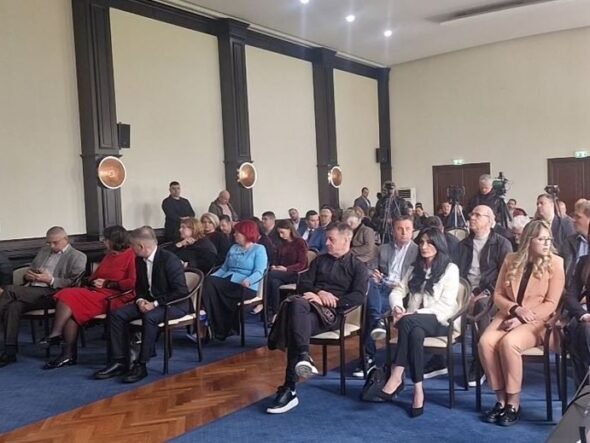 Audience seated in rows in a formal conference room during a presentation/meeting session.