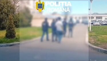 Blurry group of people standing outdoors with the Romanian police emblem in the top-left corner.