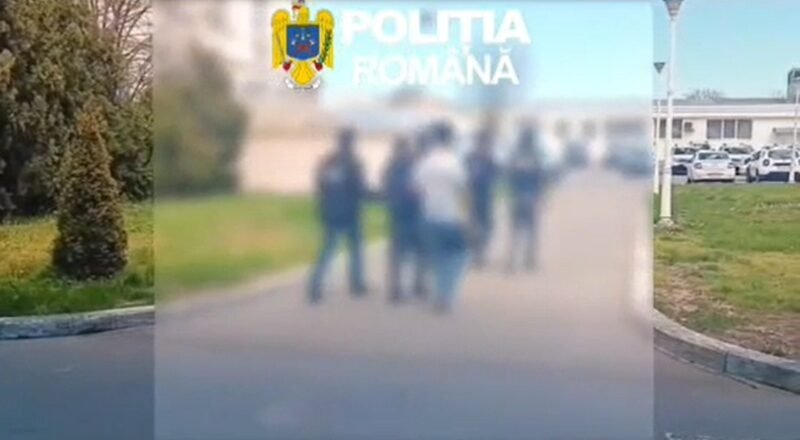 Blurry group of people standing outdoors with the Romanian police emblem in the top-left corner.