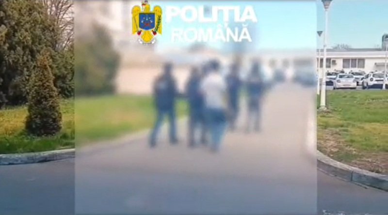 Blurry group of people standing outdoors with the Romanian police emblem in the top-left corner.
