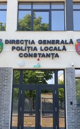 Facade of the Constanța Local Police Directorate building with Romanian and EU flags, crest shields, and glass entrance doors.