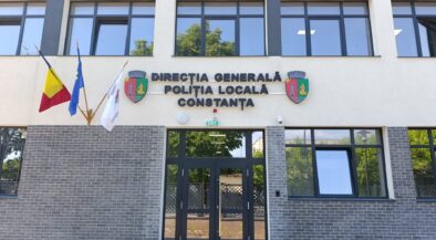 Facade of the Constanța Local Police Directorate building with Romanian and EU flags, crest shields, and glass entrance doors.