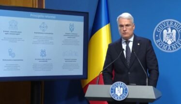 Romanian government official at a lectern with the national flag and Government of Romania insignia, delivering a presentation with a slide titled 'Principiile reformei'