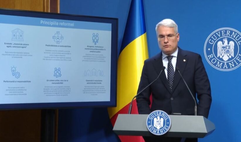 Romanian government official at a lectern with the national flag and Government of Romania insignia, delivering a presentation with a slide titled 'Principiile reformei'