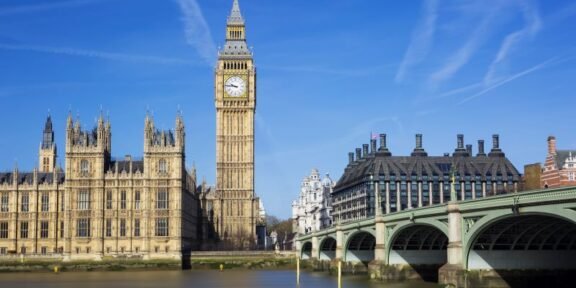 Big Ben (Elizabeth Tower) with the Houses of Parliament and Westminster Bridge across the River Thames on a sunny day in London.