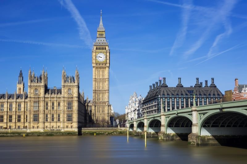 Big Ben (Elizabeth Tower) with the Houses of Parliament and Westminster Bridge across the River Thames on a sunny day in London.