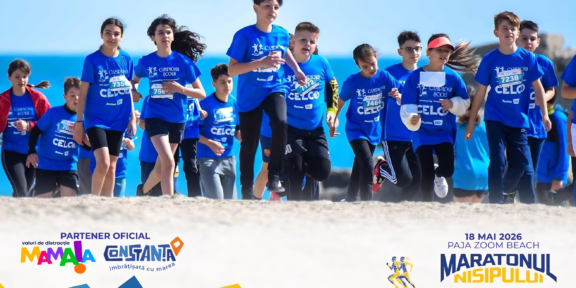 Group of children in blue shirts running on a beach during a marathon, with banners and logos visible in the foreground.