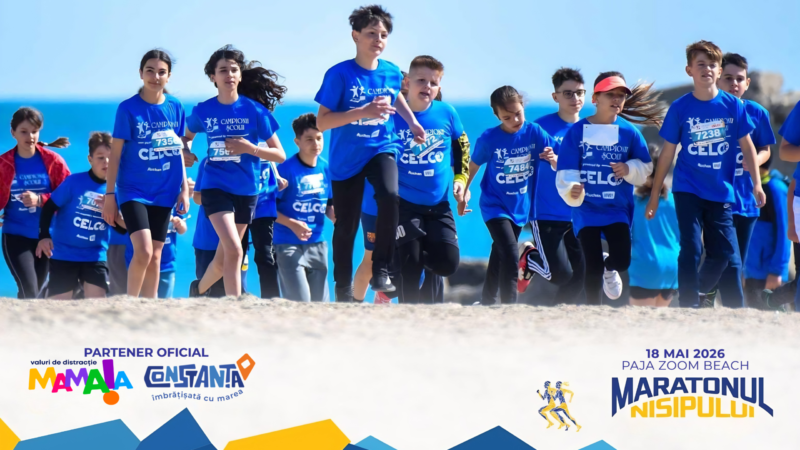 Group of children in blue shirts running on a beach during a marathon, with banners and logos visible in the foreground.