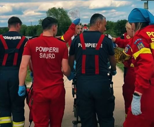 Emergency responders in red and dark uniforms gather around a patient on a wheeled stretcher outdoors during a rescue.