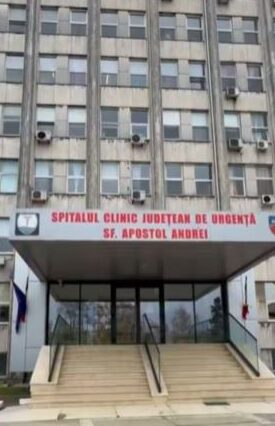 Front entrance of a large hospital building with stairs and glass doors, sign reads 'Spitalul Clinic Judetean de Urgenta Sf. Apostol Andrei'