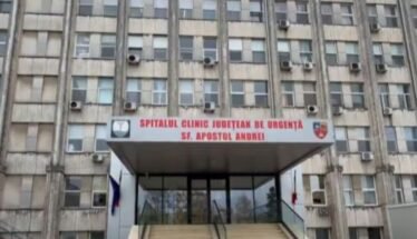 Front entrance of a large hospital building with stairs and glass doors, sign reads 'Spitalul Clinic Judetean de Urgenta Sf. Apostol Andrei'