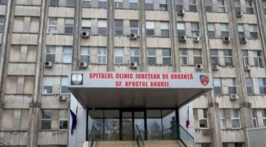 Front entrance of a large hospital building with stairs and glass doors, sign reads 'Spitalul Clinic Judetean de Urgenta Sf. Apostol Andrei'