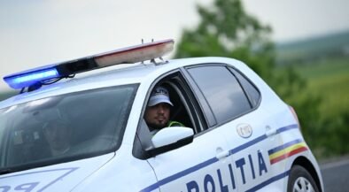 Romanian police car with blue emergency lights on; officer visible in the driver's seat.