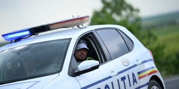 Romanian police car with blue emergency lights on; officer visible in the driver's seat.
