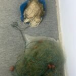 Coiled fishing nets and ropes in a blue bag and a transparent bag on a gray carpeted floor, tangled and ready for storage