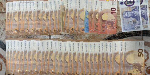 Seized euro banknotes arranged in two long rows on a patterned surface, with police logos in the corner.