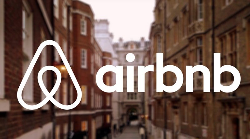 Airbnb logo overlay on a blurred city street background, brand name clearly visible